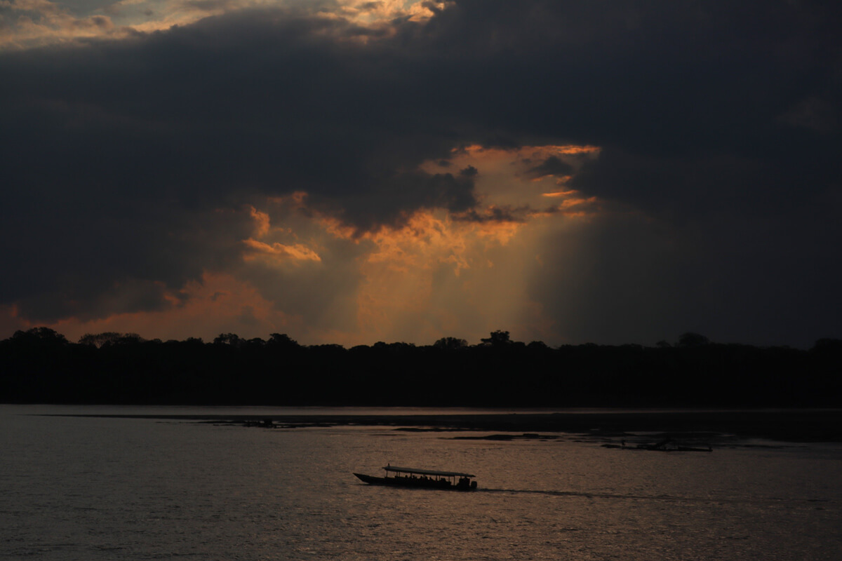 Boot op een rivier in de jungle tijdens zonsondergang