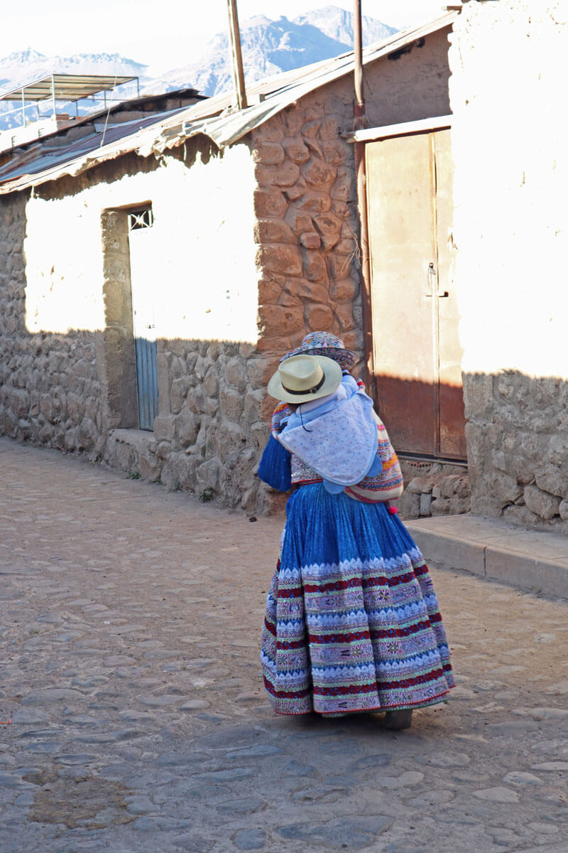 Vrouw in traditionele kleding met kind op rug